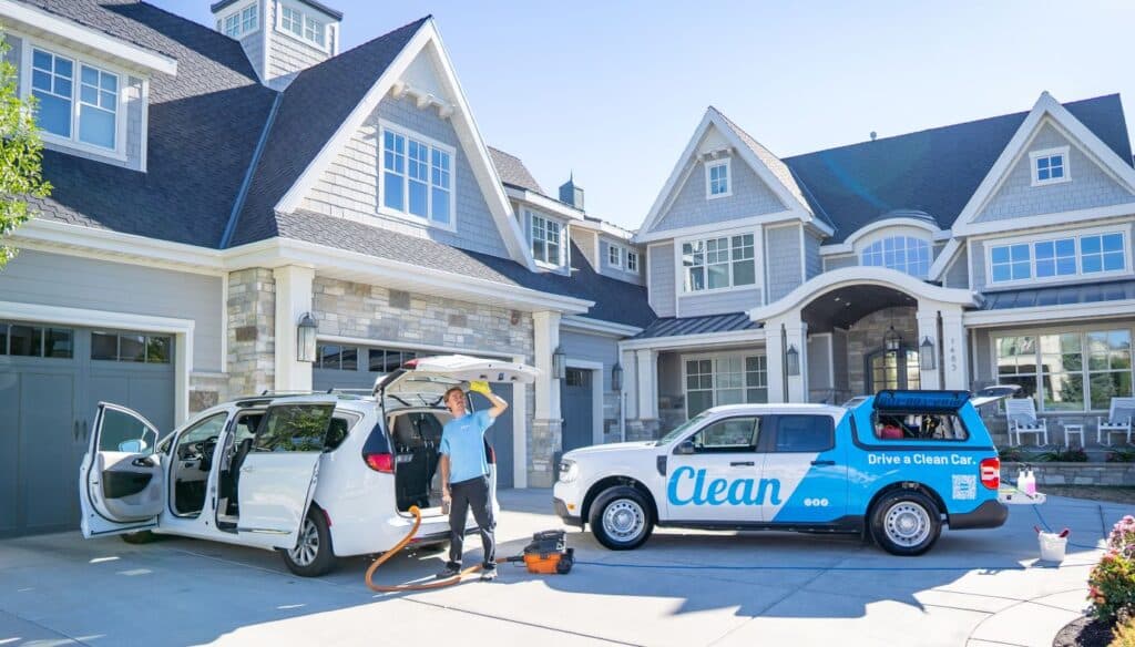 A Clean Pro details a customer’s minivan next to a Clean Mobile Detailing vehicle in a Utah driveway